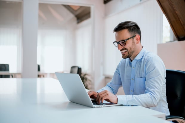 Mann arbeitet im Büro und lächelt_